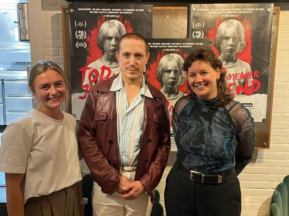 Filmpremiere ÄKSA Zwei Frauen und ein Mann vor Filmplakaten des Filmes "Tod meiner Jugend"