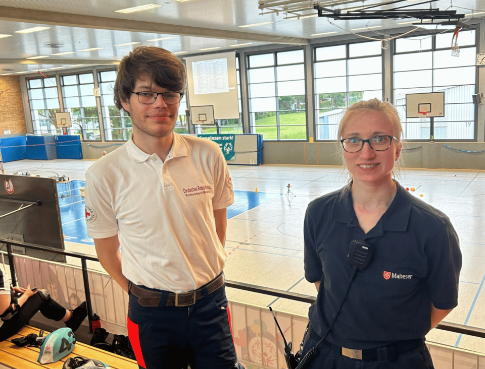 Special Olympics Zwei Personen in Einsatzkleidung auf der Tribüne einer Turnhalle