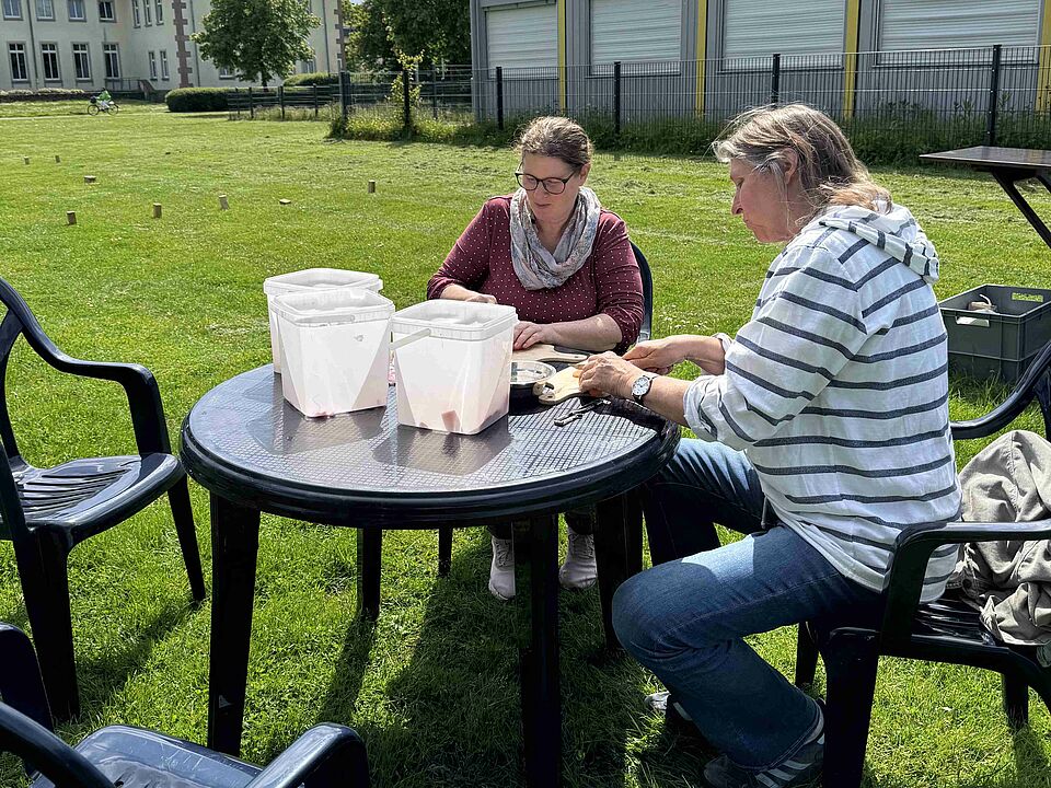 Zwei Frauen sitzen an einem Tisch und schneiden Gemüse