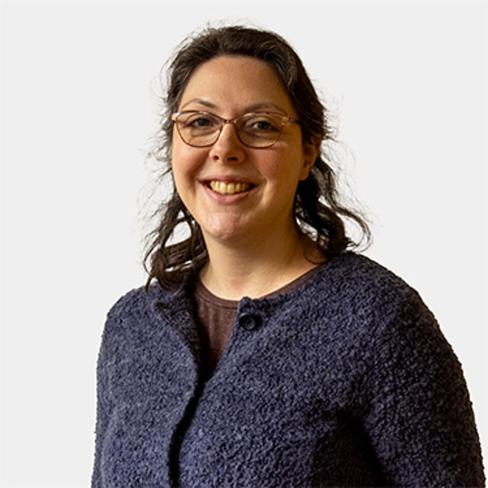 Frau mit Brille und Strickjacke vor weißem Hintergrund