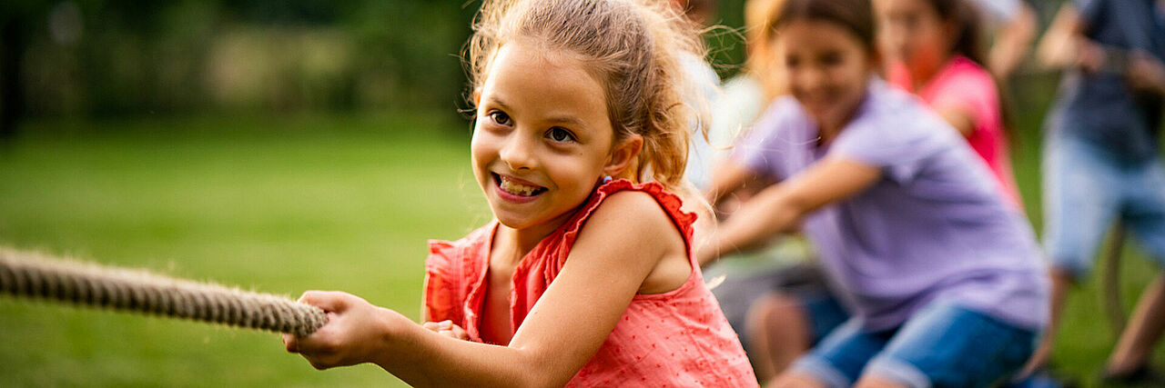 Kita Slider Mehrere Kinder machen Tauziehen, ein Kind im Vordergrund am Seil, der Rest unscharf im Hintergrund