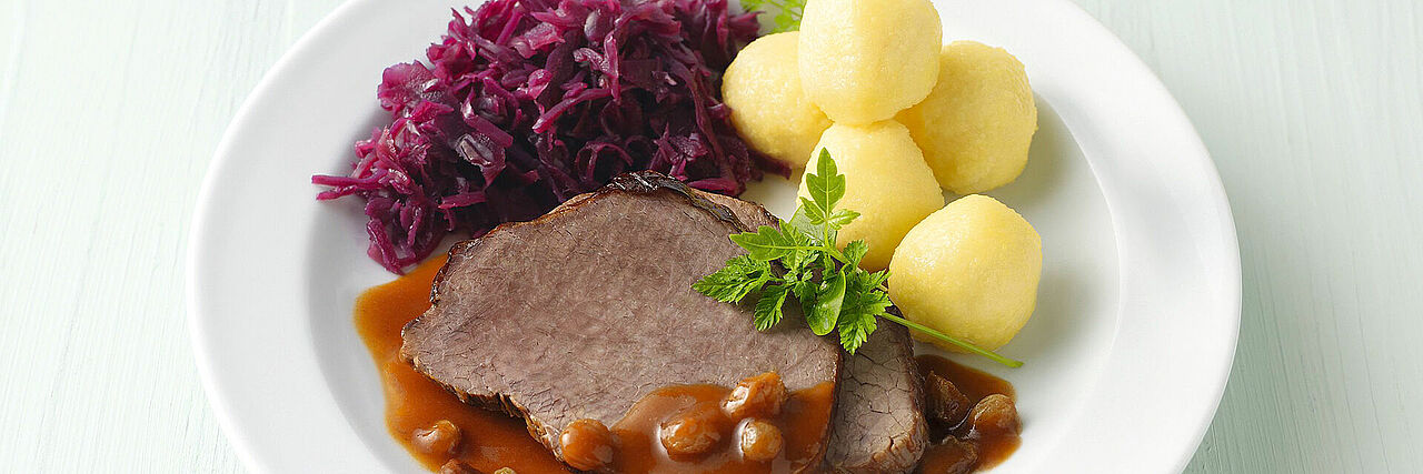 Teller mit Fleisch, Rotkohl und Kartoffelklößen
