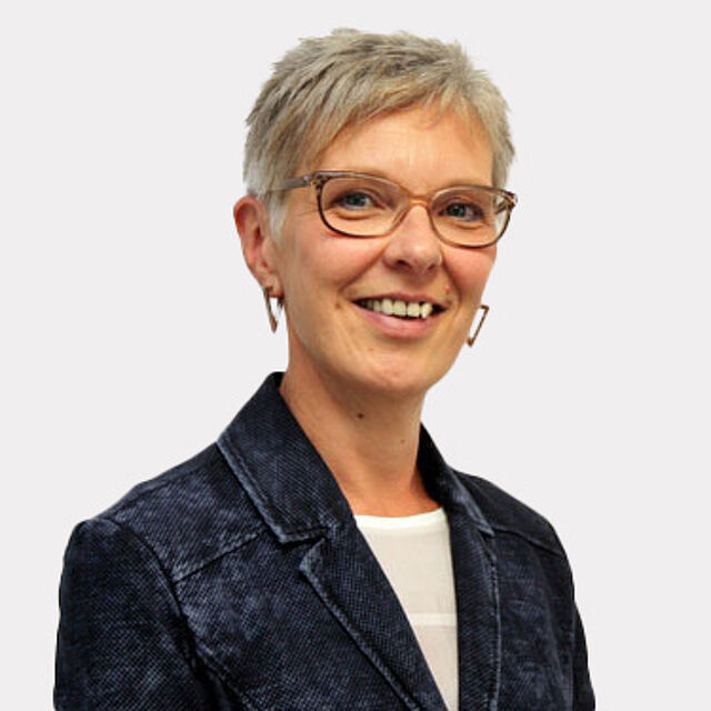 Frau mit kurzen Haaren und Brille vor weißem Hintergrund