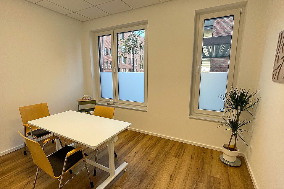 Ein Raum mit Fenster, einem eckigen Tisch und 3 Stühlen.