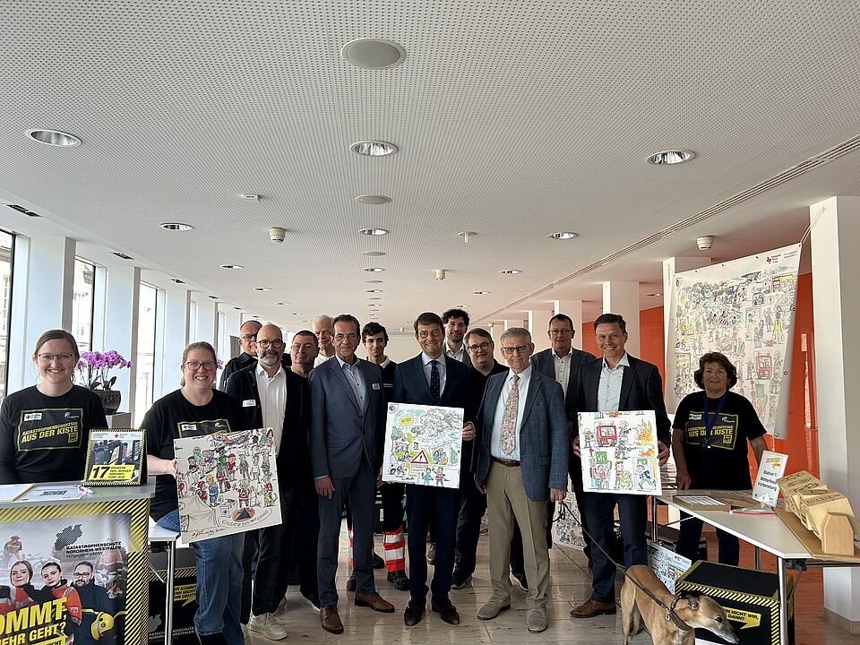Eine Gruppenbild von 15 Menschen mit Plakaten der Kampagne zum Katastrophenschutz