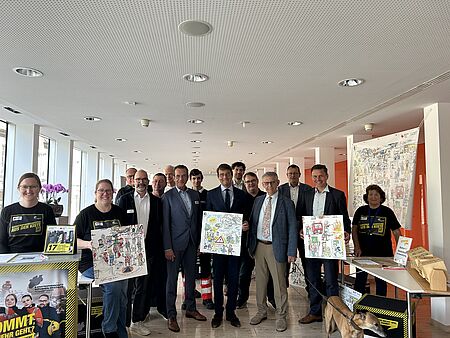 Eine Gruppenbild von 15 Menschen mit Plakaten der Kampagne zum Katastrophenschutz