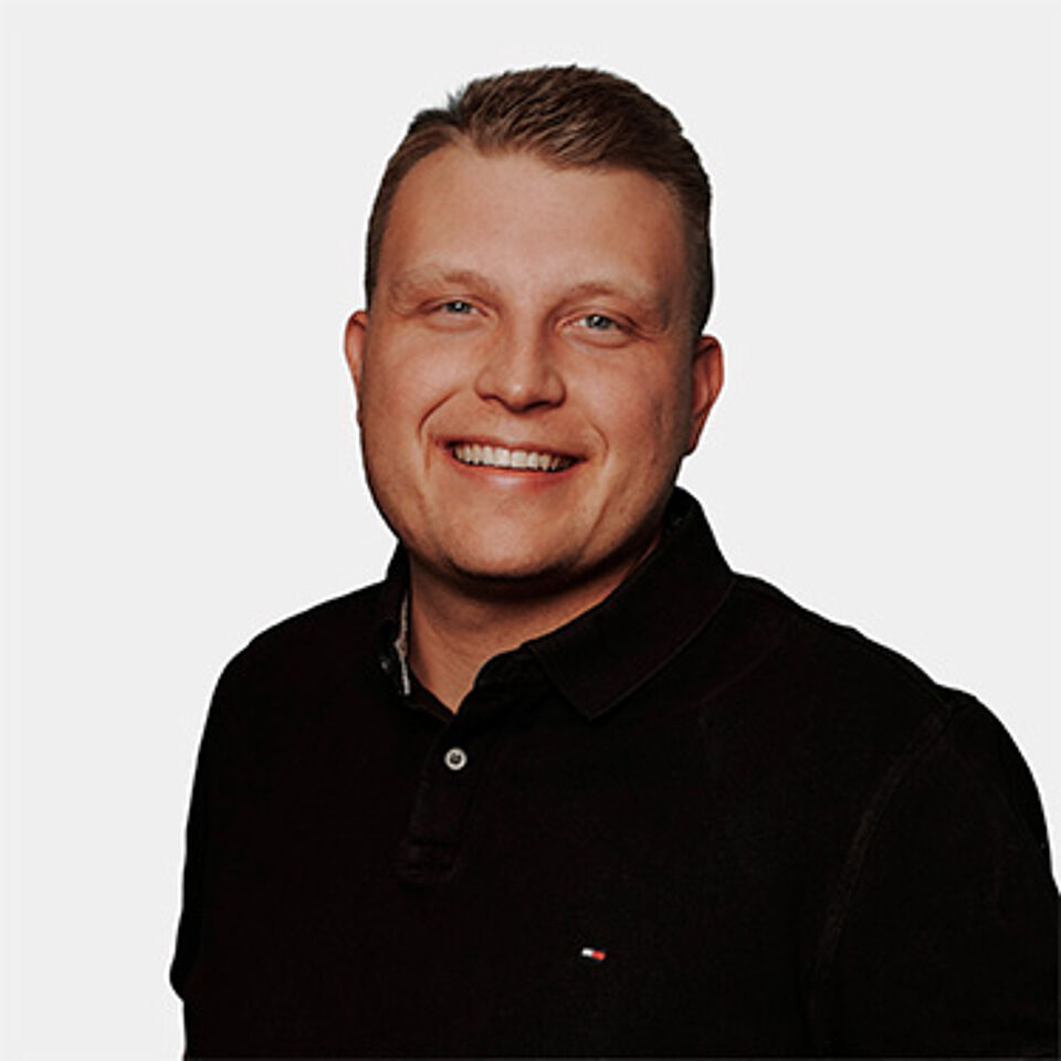 Ein Mann mit kurzen Haaren und schwarzem Poloshirt