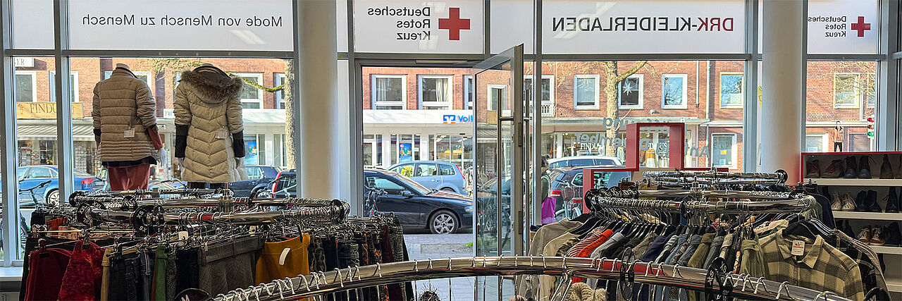 DRK-Kleiderladen Hammer Straße Innenansicht Voll behängte Kleiderständer in einem Bekleidungsgeschäft mit Blick nach außen