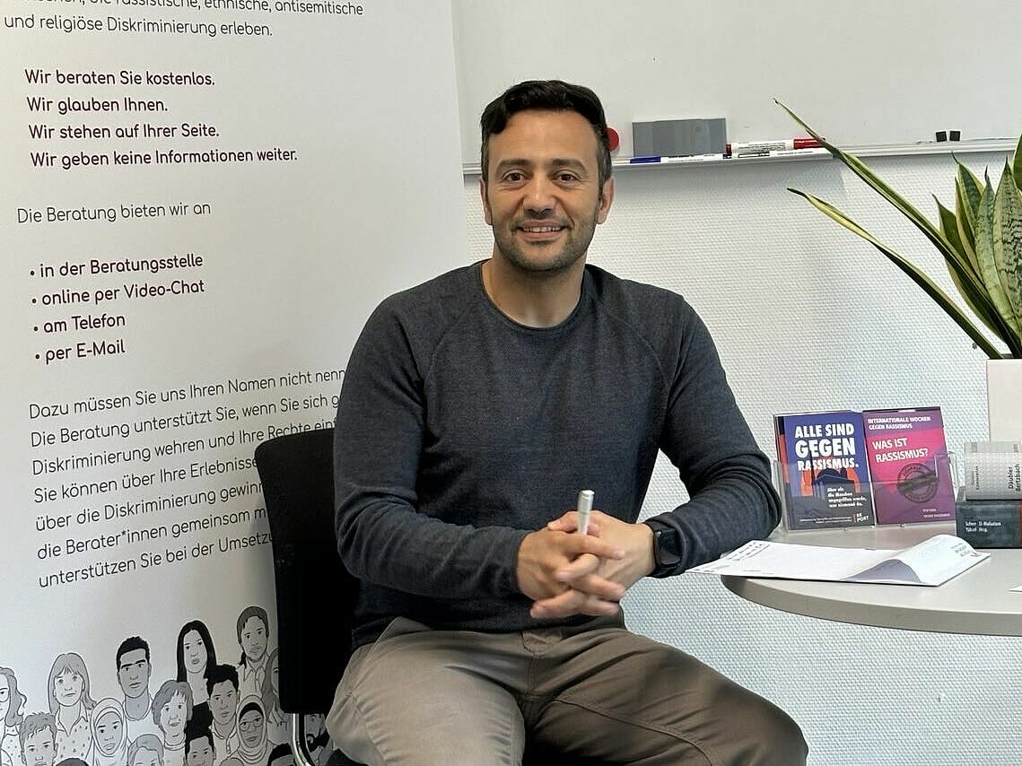 Ein Mann mit schwarzen Haaren sitzt an einem Tisch