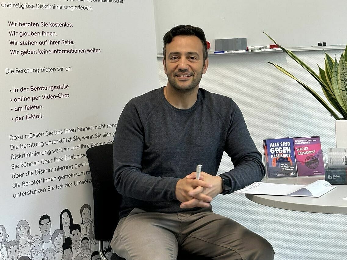 Ein Mann mit schwarzen Haaren sitzt an einem Tisch