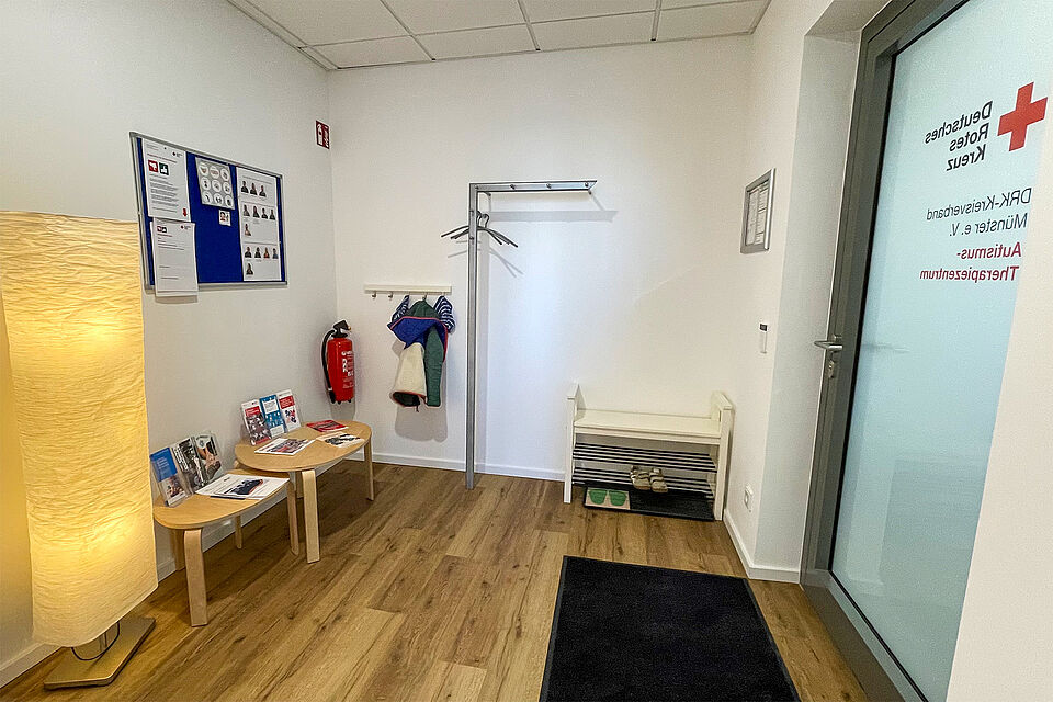 Eine Garderobe, ein Schuhregal und 2 kleine Tische hinter einer Milchglastür.