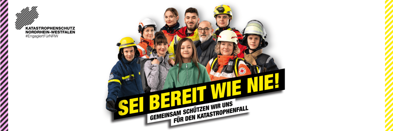 Eine Gruppe von 10 Personen, die teilweise in zivil gekleidet sind, teilweise in Einsatzkleidung der Hilfsorganisationen.