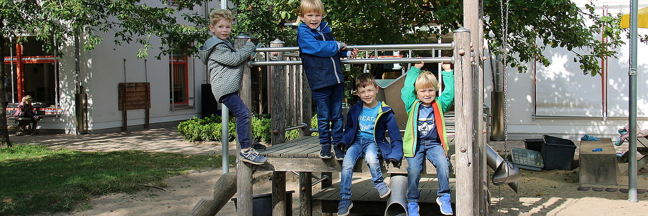 Wolkenburg Vier Kinder auf einem Klettergerüst, im Hintergrund ein Gebäude