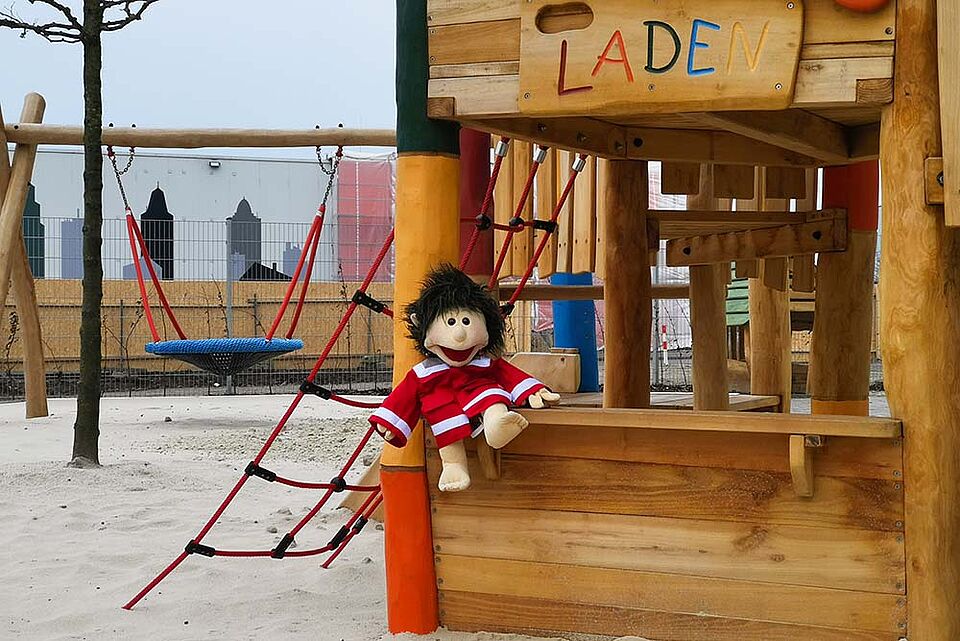 Klettergerüst aus Holz in dem eine Puppe sitzt