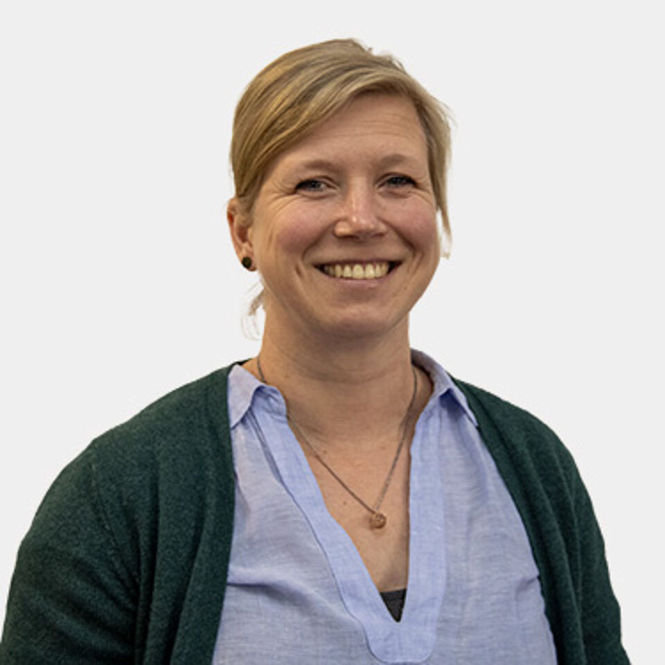 Frau mit blonden Haaren und blauer Bluse vor weißem Hintergrund