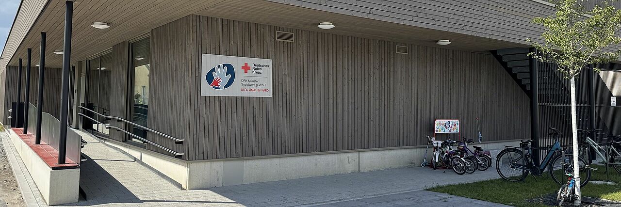 Hand in Hand Slider Gebäude mit grauer Holzfassade und Rampe