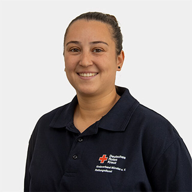 Frau mit braunen Haaren und blauem Poloshirt mit Rotkreuz-Logo
