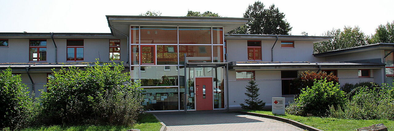 Wolkenburg Modernes Gebäude mit großen Fenstern und roter Tür umgeben von Grün