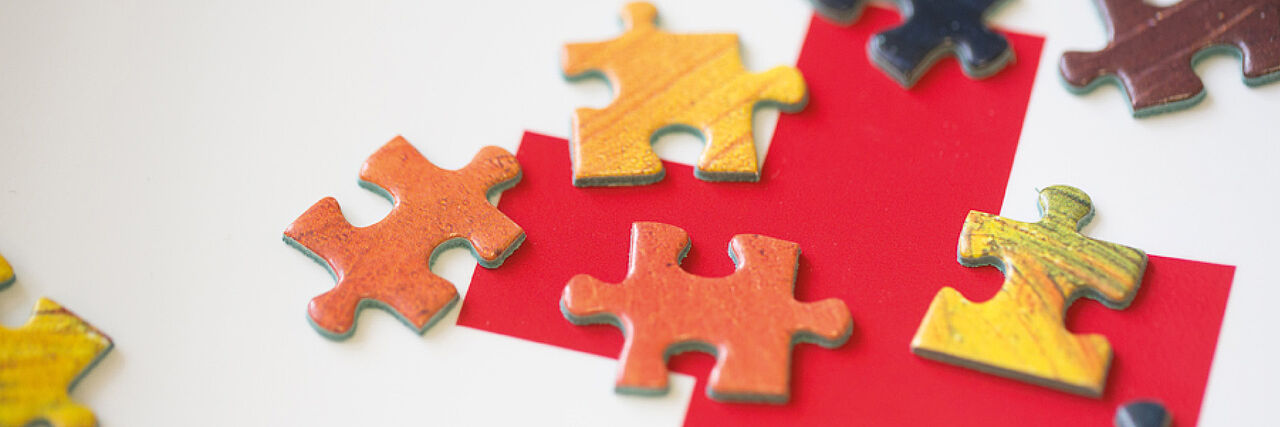 Puzzle-Teile auf einem Rotkreuz-Logo