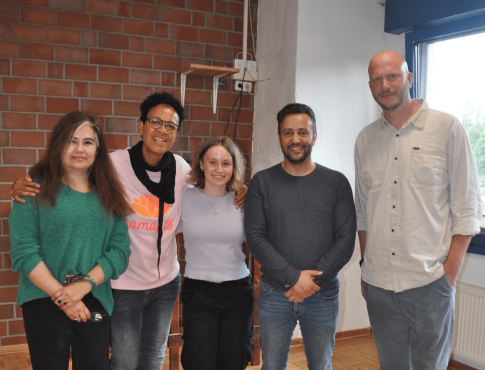 Gruppenbild Gruppenbild von fünf Personen, im Hintergrund eine Backsteinmauer