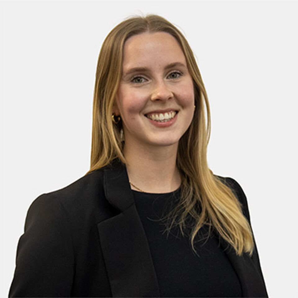 Eine junge Frau mit blonden langen Haaren und schwarzem Blazer