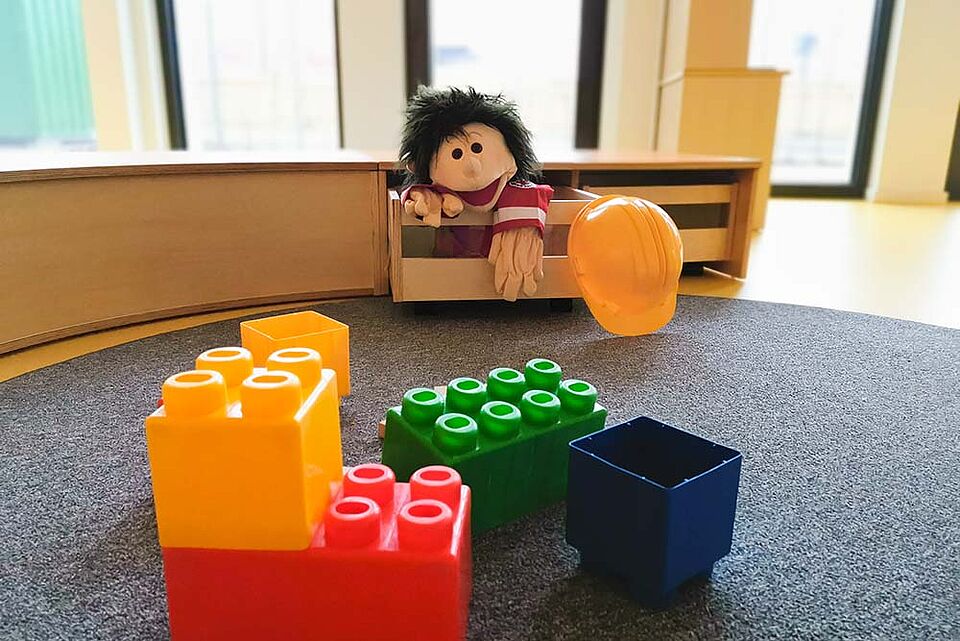 Holzmöbel und Teppichboden, auf dem bunte Legosteine liegen