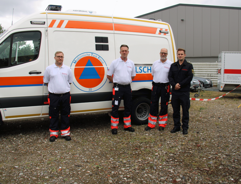Vier Männer stehen vor einem Einsatzfahrzeug