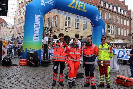 Vier Personen in Einsatzkleidung vor einem blauen Bogen mit der Beschriftung "Ziel"