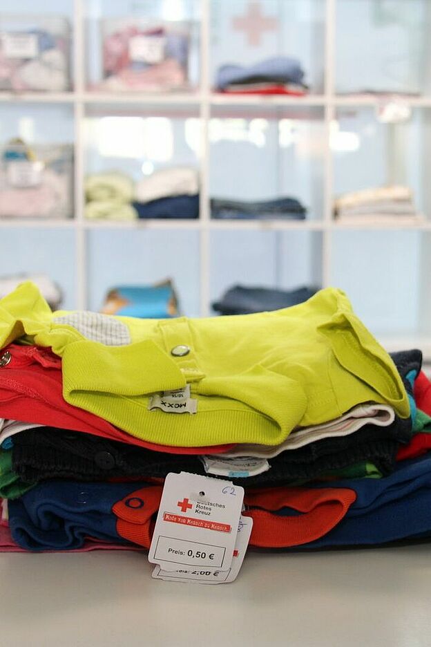 Bunte Kleidung liegt in einem weißen Regalfach