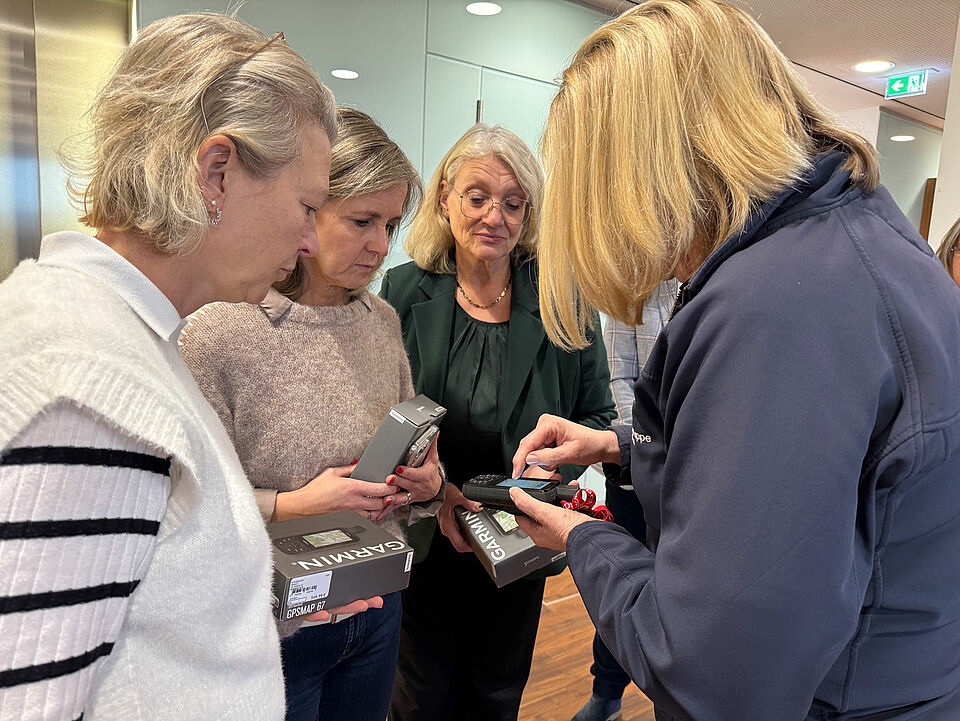 GPS-Geräte Vier Frauen stehen im Halbkreis, in ihrer Mitte ein GPS-Gerät