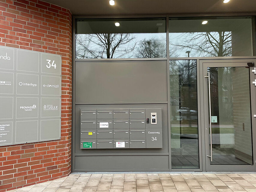 Ein breites gläsernes Portal mit dunkelgrauem Rahmen und Beschilderung.