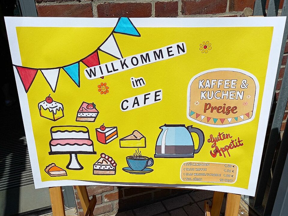 Ein gelbes Schild auf dem der Kaffee und Kuchen beworben wird