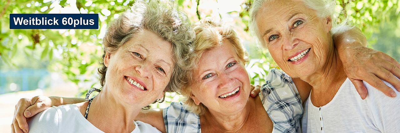 Weitblick 60plus Drei Seniorinnen umarmen sich, im Hintergrund ein Baum