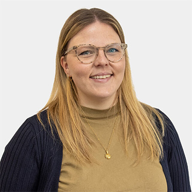Frau mit blonden Haaren und Brille vor weißem Hintergrund