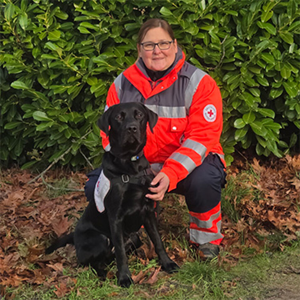 Eine Frau in Einsatzbekleidung mit schwarzem Hund