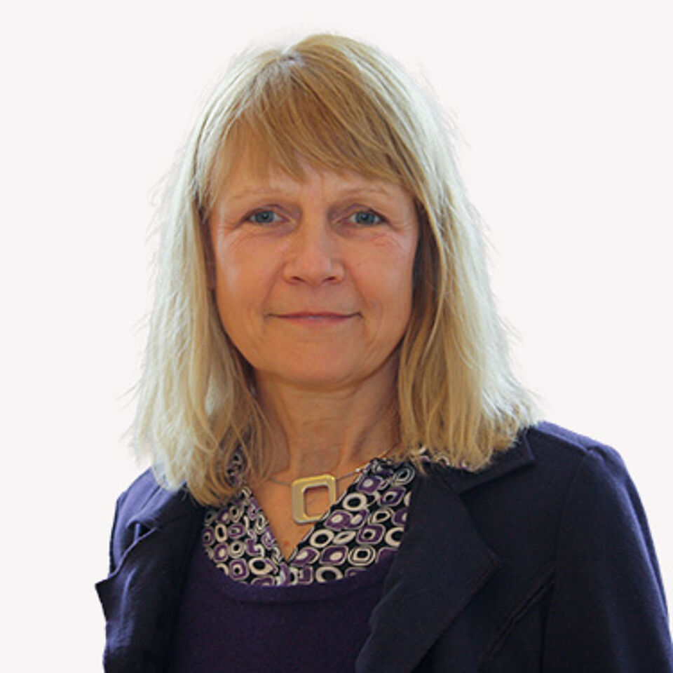 Frau mit blonden Haaren und blauem Oberteil vor weißem Hintergrund