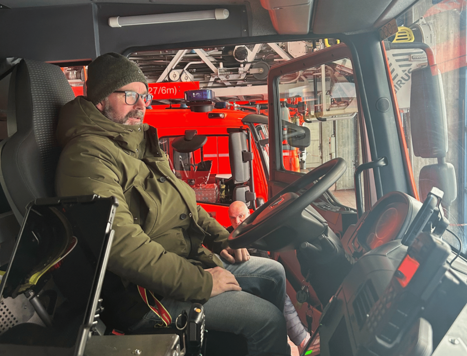 Eine Person mit Winterjacke und Mütze sitzt auf dem Fahrersitz eines Feuerwehrautos
