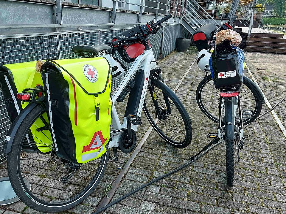 Einsatzfahrräder Zwei weiße Fahrräder mit Satteltaschen und DRK-Beschriftung