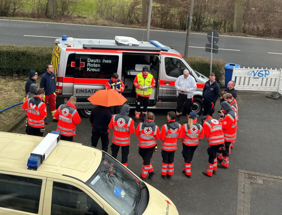 Eine Gruppe von Einsatzkräften steht um den Einsatzleitwagen herum zur Einsatzbesprechung.