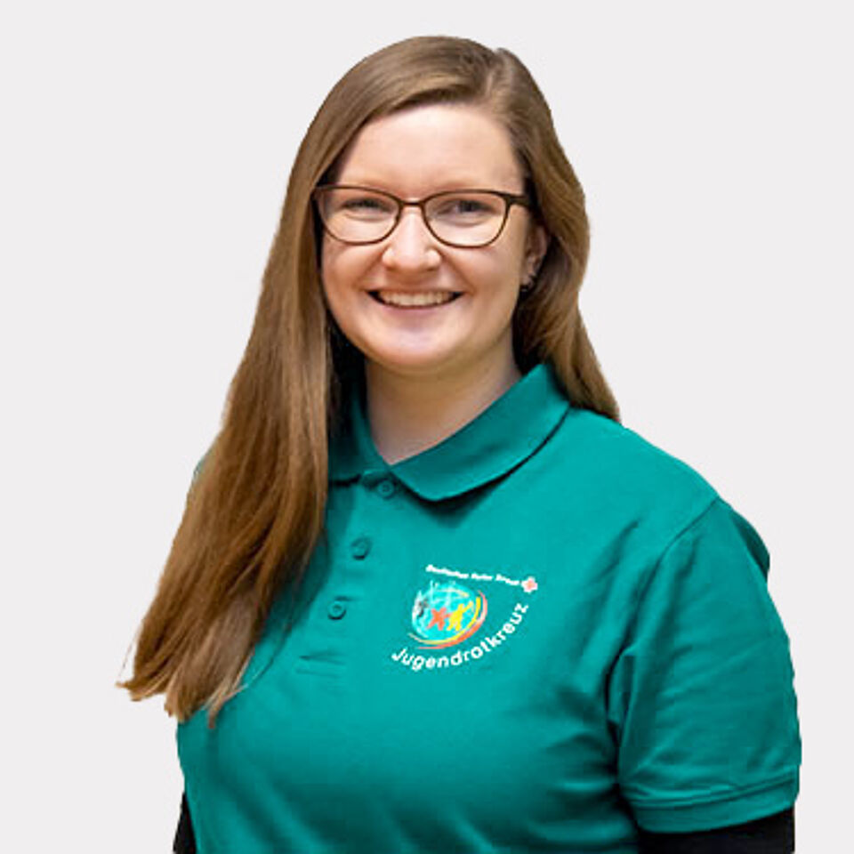 Frau mit langen braunen Haaren, Brille und türkisem JRK-Poloshirt.