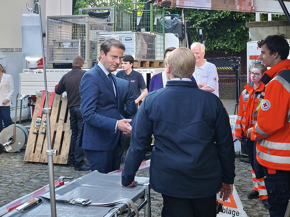 Fahrzeuge und Wagen im Hintergrund, im Vordergrund Gespräch zwischen Einsatzkräften und Vertretern der Bezirksregierung