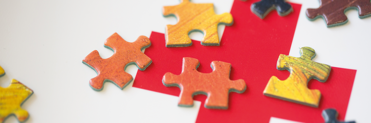 Puzzle-Teile auf einem Rotkreuz-Logo