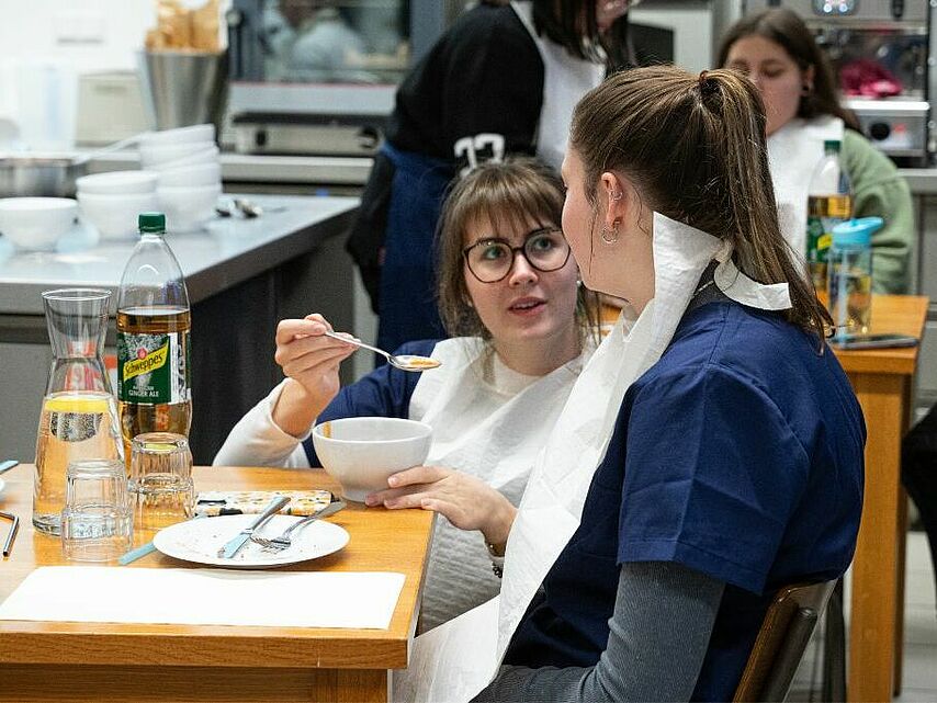 Eine junge Frau reicht einer anderen Person Essen an.