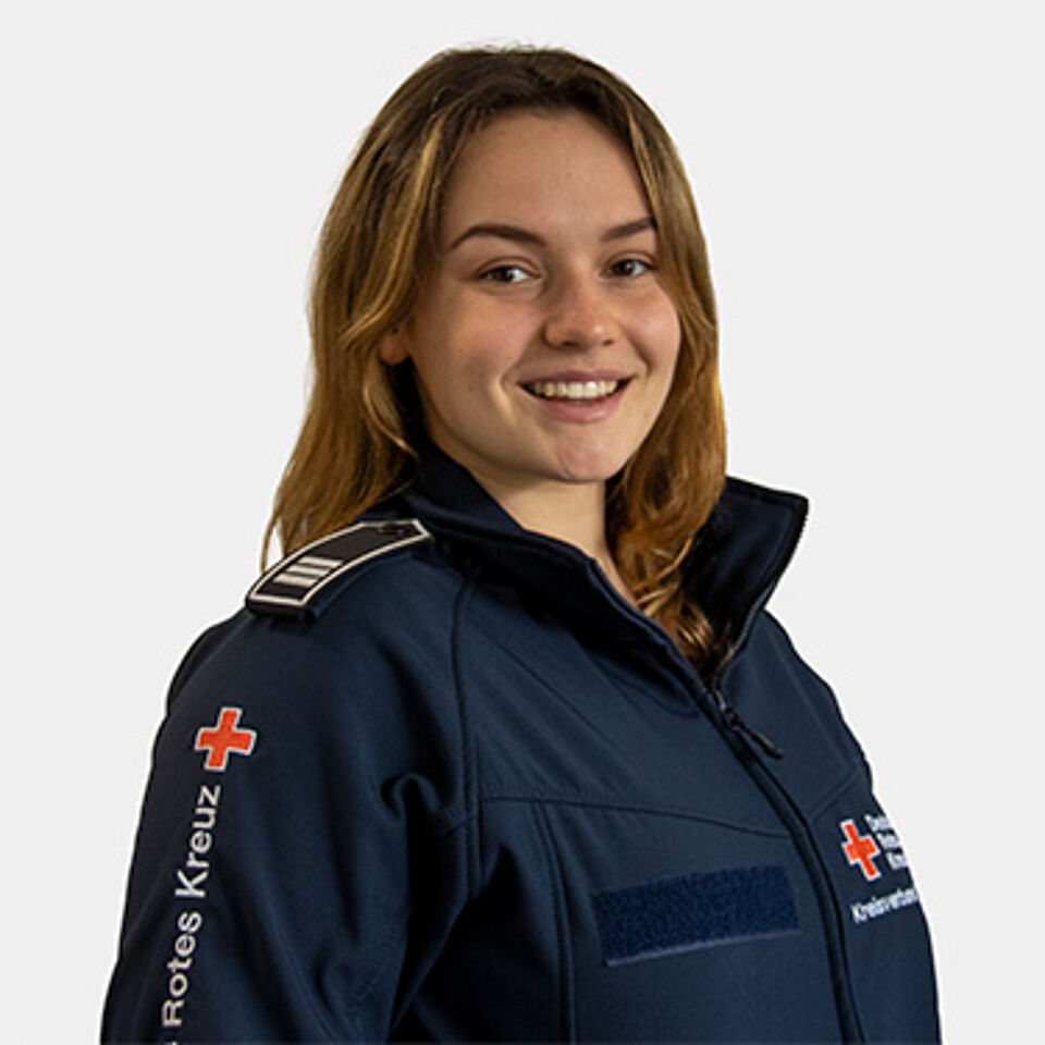 Eine junge Frau mit braunen Haaren und blauer Jacke.