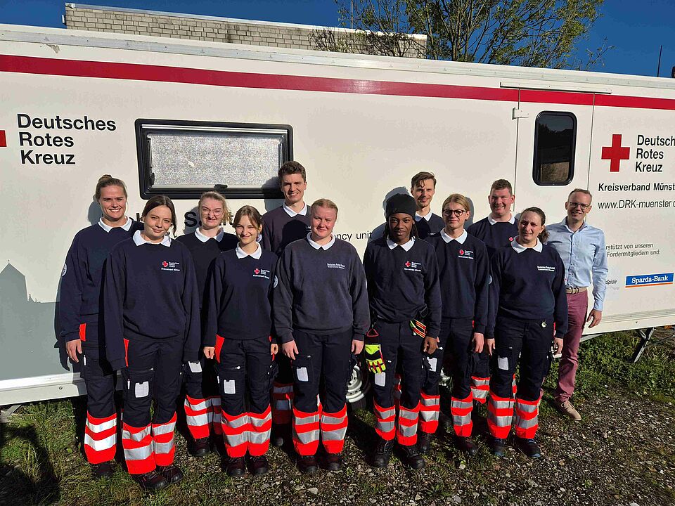 12 Personen in DRK-Einsatzkleidung vor einer Unfallhilfsstation