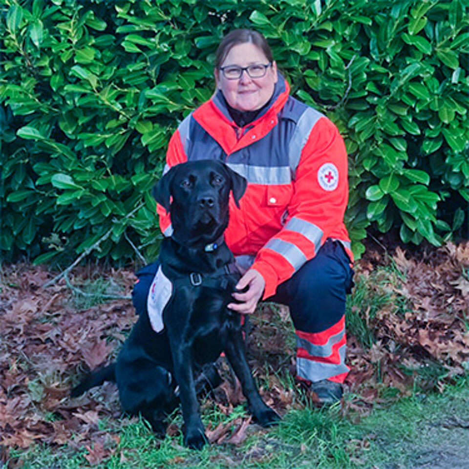 Eine Frau in Einsatzbekleidung mit schwarzem Hund