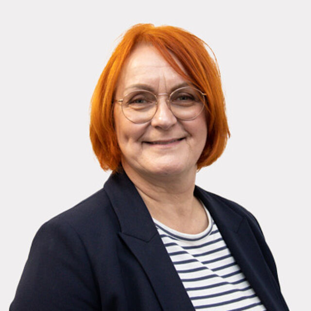 Frau mit roten Haaren, gestreiftem T-Shirt und Blazer vor weißem Hintergrund