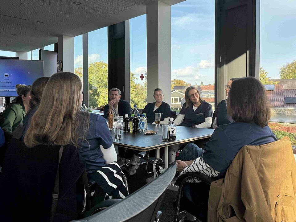 Auftakt StudiPUK Personen sitzen an einem Tisch, auf dem Getränke und Snacks stehen, zusammen