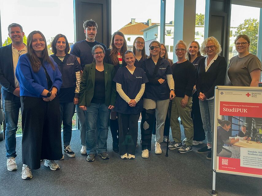 Gruppenbild von 14 Personen neben einem "StudiPUK" Plakat
