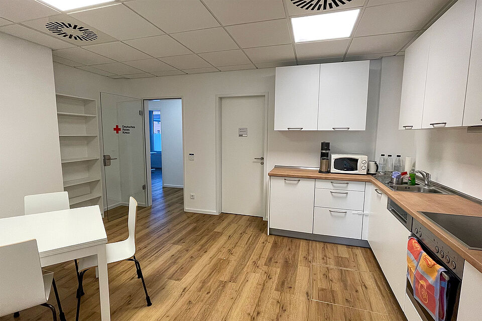 Eine weiße Küche mit brauner Arbeitsplatte, ein Küchentisch mit Stühlen.